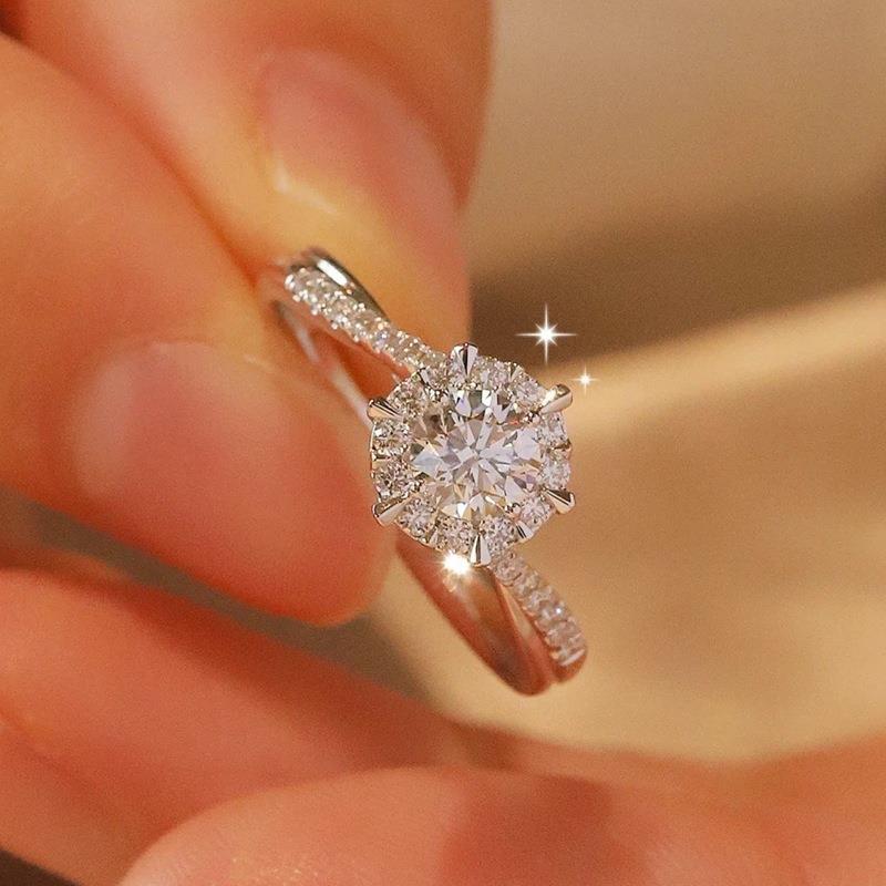Diamond ring held between fingers against a blurred background